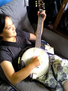 Woman playing a banjo guitar Banjitar player.jpg
