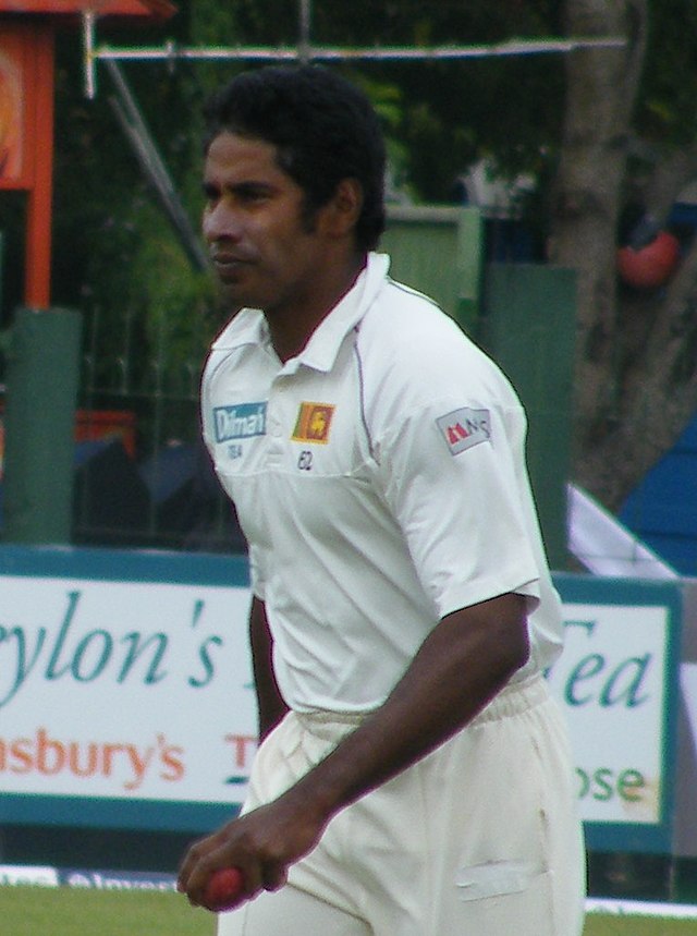 Vaas, dressed in cricket whites and holding cricket ball in left hand, preparing to start his bowling run up.