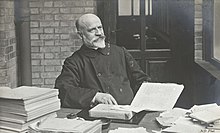 Photograph of Jean-Vincent Scheil at a desk with piles of books and paper