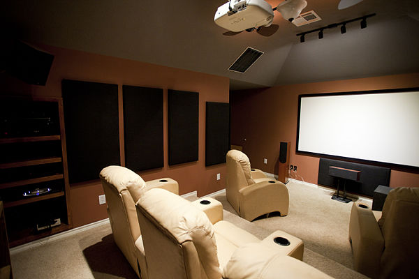 A dedicated home cinema room with acoustic treatment, professional wiring, equipment and speaker placing, and a digital projector and screen