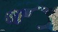 Photo couleur aérienne de plusieurs îles boisées, au milieu d'une étendue d'eau bleue.