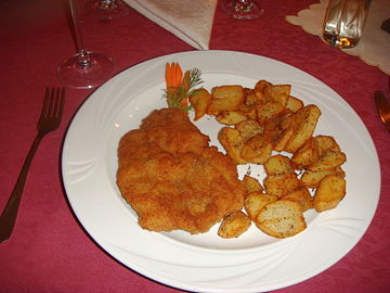 One of typical ways of serving kotlet schabowy pork cutlet on a plate with home fries.