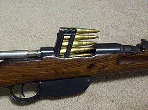 Een 1895 Mannlicher geweer geladen met een 5-round pack.  De geleegde verpakking valt eruit door de van onderaf geopende winkelschacht