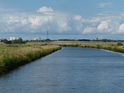 Motzener Kanal, Blick auf Straßendamm für neue B 212, Wasserturm (groß) und Kirchturm von Bremen-Blumenthal