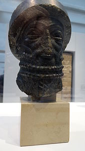 Foto di un busto in pietra nera che rappresenta Hammurabi.