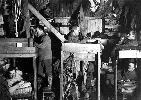 Photo of five men lounging in bunks crowded with hanging gear