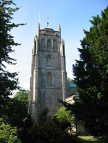 Square stone tower partially obscured by trees.