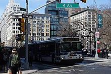 A green rectangular sign is hanging horizontally, with "4 Av" in mixed case.