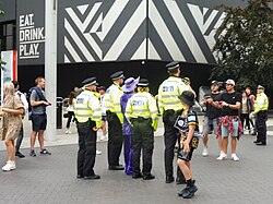 Metropolitan Police officers taking a photograph with a member of the crowd on the Olympic Way on the day of the 2023 Challenge Cup Final.