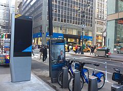 A Citi Bike pay station in Midtown Manhattan, with a few bikes shown at right. A LinkNYC booth for free internet and phone calls is located on the left.