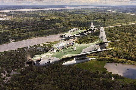 A pair of Brazilian Air Force Embraer A-29 Super Tucanos in flight over the Amazon Rainforest.