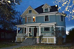 Photograph of the Blackaby House at night, a two-story, wooden house with a broad front porch and complex roof