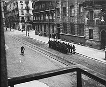 Photographie prise clandestinement depuis un balcon qui montre une section allemande défilant dans le boulevard Édouard-Rey à Grenoble.
