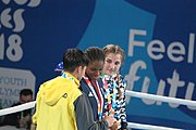 Deutsch: Boxen bei den Olympischen Jugendspielen 2018 Tag 12, 18. Oktober 2018 - Medaillenzeremonie im Leichtgewicht der Mädchen - Gold: Caroline Sara DuBois (Großbritannien), Silber: Porntip Buapa (Thailand), Bronze: Oriana Saputo (Argentinien); Medaillenübergabe durch Habu Gumel (IOC, Nigeria), Geschenkübergabe durch Raymond Silvas (USA, AIBA). English: Boxing at the 2018 Summer Youth Olympics on 18 October 2018 – Girl's Lightweight Medal Ceremony - Gold: Caroline Sara DuBois (Great Britain), Silver: Porntip Buapa (Thailand), Bronze: Oriana Saputo (Argentina); Medal handover by Habu Gumel (IOC, Nigeria), Gift presented by Raymond Silvas (USA, AIBA). Español: Boxeo en los Juegos Olímpicos Juveniles de Verano de 2018 en 18 de octubre de 2018 - Ceremonia de la Medalla de peso ligero para niñas - Oro: Caroline Sara DuBois (Gran Bretaña), Plata: Porntip Buapa (Thailand), Bronce: Oriana Saputo (Argentina); Entrega de medallas por Habu Gumel (COI, Nigeria), Regalo presentado por Raymond Silvas (EE. UU., AIBA).