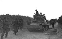 Un L6/40 décoré des insignes allemands passe au côté d'une colonne de soldats allemands en Albanie occupée, septembre 1943.