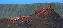 Groupe de randonneurs se reposant sur un cône volcanique de l'Enclos Fouqué.