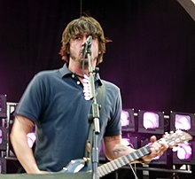 Dave Grohl sings and plays the guitar atop a stage.