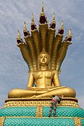 Man painting in gold a statue of the Buddha