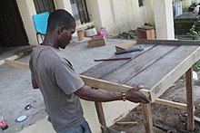 Photographie d'un homme ajustant deux pièces de bois.