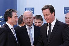 Cameron and Foreign Secretary William Hague speaking to NATO Secretary General Anders Fogh Rasmussen at the London Conference on Libya, 29 March 2011 NATO Secretary General (5570935879).jpg