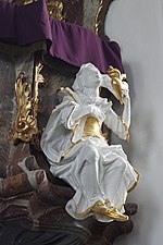 Vue de gauche, statue d'un jeune homme drapé de blanc avec parures d'or, bras droit levé vers le ciel, accroché à la chaire de l'église.
