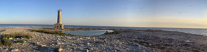 Isola di roccia nuda con un faro fatiscente e il lago Erie sullo sfondo