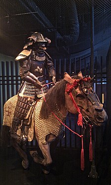 Рекреација на оклопен самурај кој јава коњ, кој има коњски оклоп ума јорои или багаи (2).