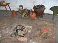 small brick hearth; in the background, a basket with clumps of peat and a bell-shaped earthenware, used to snuff out the fire