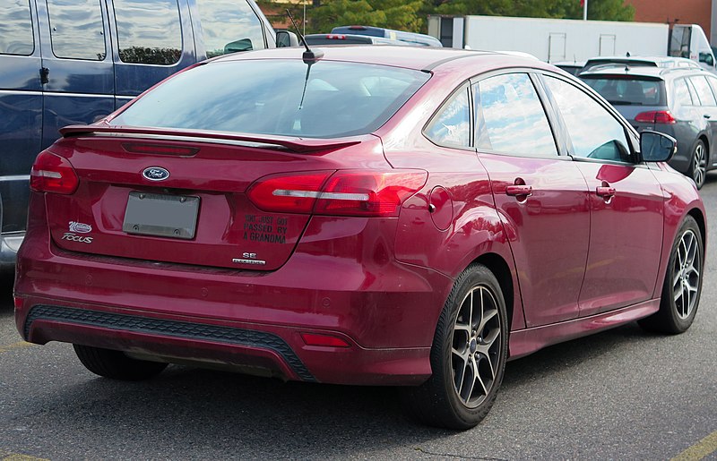 File:2015 Ford Focus SE sedan with SE Sport Package in Ruby Red Tinted Clearcoat Metallic, Rear Right, 10-05-2022.jpg