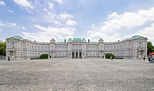 A large palace built of white stone in neo-baroque style. The facade is adorned with columns.