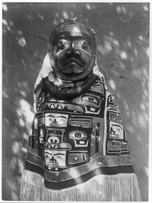 Kwagu'l woman wearing a fringed Chilkat blanket (worn backwards), a hamatsa neckring and mask representing a deceased relative who had been a shaman. Photograph by Edward S. Curtis c. 1883. A Tluwulahu costume - Qagyuhl - Edward S Curtis - LC-USZ62-52211.jpg