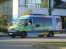 Photographie en couleurs d’un minibus aux couleurs des lignes village.