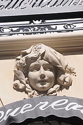 Beaux Arts mascaron with lavander in its hair, above a window of the parfumery of Jacques and Pierre Guerlain