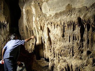 Man striking stalactite formation to produce musical notes.