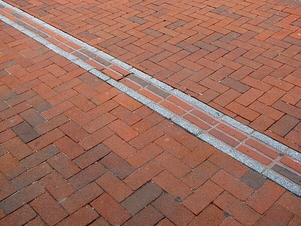 Freedom Trail marker through a red brick sidewalk