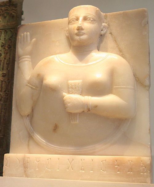 A Sabaean gravestone of a woman holding a stylized sheaf of wheat, a symbol of fertility in ancient Yemen.