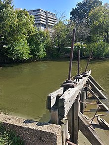 The Chesepeake and Ohio canal terminus at milepost zero. The photo shows the remains of Waste Weir #1, and where the gravity dam used to be. The "Watergate West" building is in visible in the background. C&O Canal water gate with Watergate complex in background.jpg