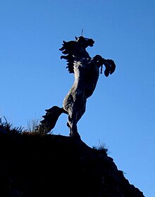 A monumental sculpture by Tighe O'Donoghue/Ross created in patinated ferro-cement of a war horse with helmet and broken chains atop an outcrop along the N22 roadway near Killarney, County Kerry, Ireland Capall Mor.jpg