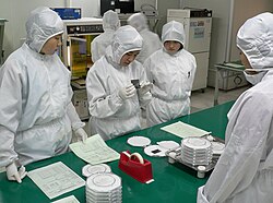 Technicians wearing clean room suits inspect a semiconductor wafer Cleanroom suit.jpg