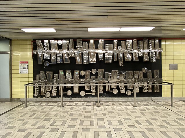 The sculpture on the concourse level, Rhythm Of Exotic Plants, is "donated by Rio Algom Ltd. for the enjoyment of TTC riders".
