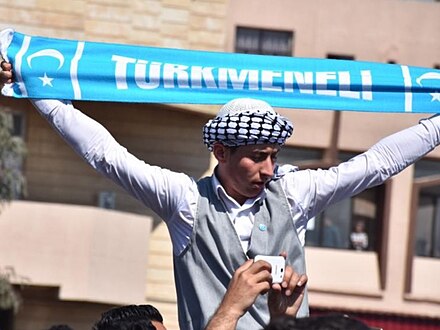 An Iraqi Turkmen youth holding a Turkmeneli scarf.