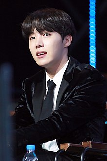 J-Hope in a black suit against a black background