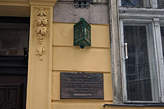 Zdjęcie. Fragment kamienicy. Pomiędzy oknem a drzwiami wejściowymi wmurowana tablica z informacją, że w tym domu mieszkał Jerzy Turowicz. Powyżej umieszczono numer kamienicy 7.