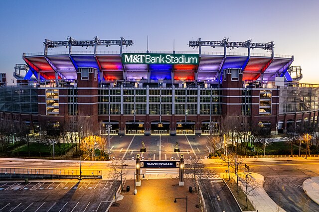 An aerial photograph of M&T Bank Stadium at night lit with red, white, and blue lights.