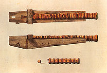 Blick von oben und von der Seite einer langen, schlanken Kanone, die an einem massiven Holzwagen aus einem Stück Holz befestigt ist