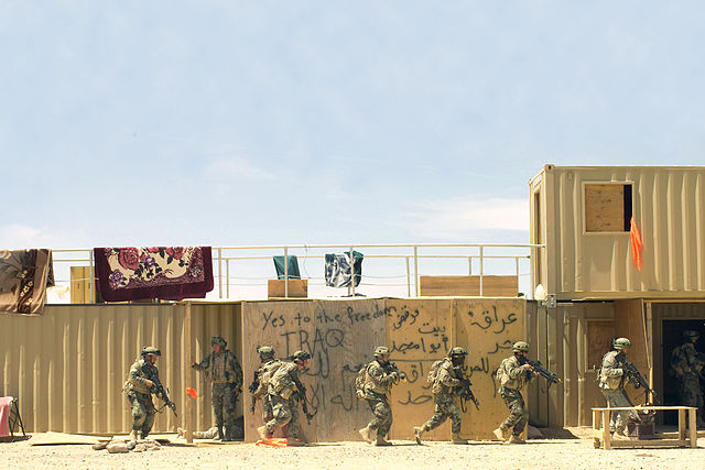 Soldiers move forward to search a building during training at the National Training Center. Long known for large-scale tank vs. tank battles, NTC now 