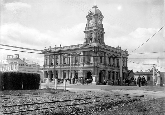 View of the (Chief) Post Office in Palmerston North, (opened in 1906) with the business premises of G H Bennett (booksellers, stationers & newsagents)