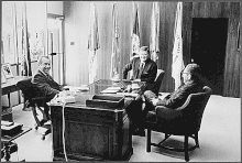 President Richard Nixon, with Henry Kissinger and John Wayne, sitting at the unnamed mahogany desk in his office at La Casa Pacifica President Richard Nixon with Henry Kissinger and John Wayne San Clemente.gif
