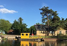 View of the "River Cam Conservators" boat and buildings at Clayhithe taken from The Bridge Pub on the opposite bank. River Cam Conservators - Clayhithe - 2017-06-09 6PM.jpg