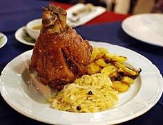 Schweinshaxe served with fried potatoes and sauerkraut at a restaurant